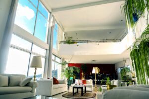 Světlý vzdušný prostor s galerií celý v bílé barvě s akcenty tmavého nábytku, červených doplňků a exotické zelene.